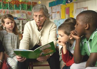 Senior lisant à un groupe d'enfants
